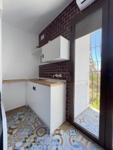 una cocina con armarios blancos y una pared de ladrillo en Moscatel - Harbor's Light, en Villajoyosa