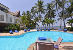 a swimming pool with chairs and a table and the ocean at Severin Sea Lodge in Mombasa
