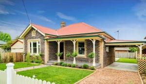 a brick house with a white fence in front of it at Carisbrook Cottage in Armidale