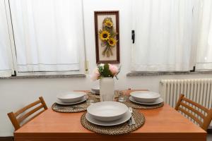 a dining room table with plates and a vase of flowers at Dolce Riviera Marina Centro in Rimini