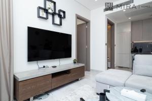 Stylish 1BR in Peninsula Five Views & Pool في دبي: غرفة معيشة مع تلفزيون بشاشة مسطحة على الحائط