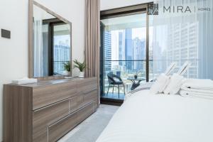 Stylish 1BR in Peninsula Five Views & Pool في دبي: غرفة نوم مع مرآة كبيرة وسرير كبير