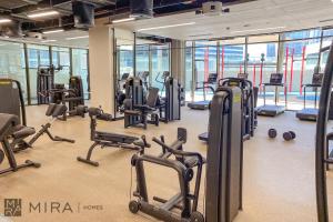 Stylish 1BR in Peninsula Five Views & Pool في دبي: صالة ألعاب رياضية مع الكثير من أجهزةالجري ودراجات ممارسة الرياضة