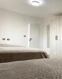 a white bedroom with two beds and a cabinet at Sol Rooms in Shkodër +17 photos