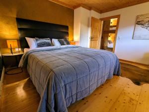 a bedroom with a large bed with a blue blanket at Chalet Sonnberg Bramberg in Bramberg am Wildkogel +35 photos