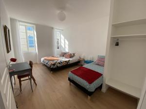 a bedroom with a bed and a desk and a table at Location maison l'embellie in La Tremblade +12 photos