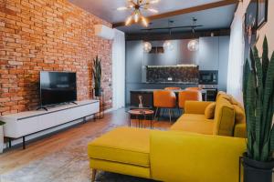 a living room with a yellow couch and a brick wall at Charlotte Piata Unirii - Free Private Parking 2bedrooms Apartment in Oradea