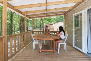 Bretagne-dʼArmagnacにあるMobilhomes Camping Lacs d'Armagnacの二人の女性がデッキのテーブルに座っている