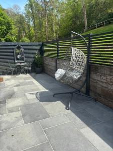 a swinging chair on a patio next to a fence at Holly studio in Midhurst