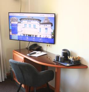a computer monitor on a desk with a chair at Hotel Adler & Eventlocation GmbH in Itzehoe