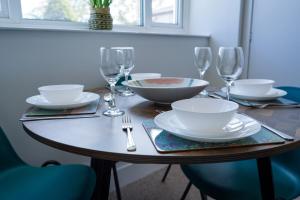 a table with plates and bowls and wine glasses at Park House - 3 bedroom in Portsoy