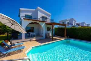 a villa with a swimming pool in front of a house at Villa Aristotelis in Argaka