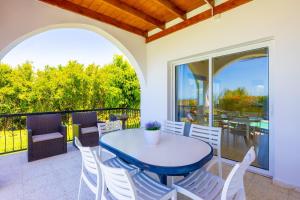 a patio with a blue table and white chairs at Villa Aristotelis in Argaka