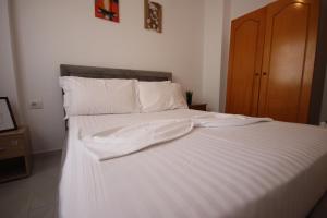 a large white bed with white sheets and pillows at Ionian Blue Apartament II in Himare