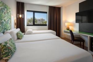 a hotel room with two beds and a tv at Catalonia Málaga in Málaga