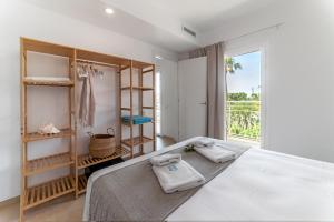 a white bedroom with a bed and a window at Bamblue Boutique Apartments in Pineda de Mar