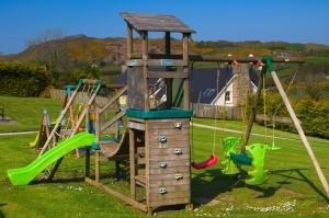 an outdoor playground with a slide and swings at Charming Coastal Cottages by Portsalon Beach in Portsalon