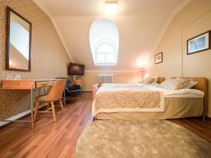 a hotel room with a bed and a desk and a mirror at Hotelli-Ravintola Mäntän Klubi in Mänttä
