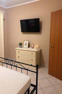 a bedroom with a dresser with a tv on the wall at Annette Home Scafati-Pompei in Scafati