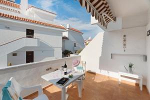 a white balcony with a white table and chairs at Serene Terrace And Pool in Playa de las Americas