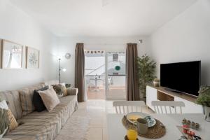 a living room with a couch and a tv at Serene Terrace And Pool in Playa de las Americas