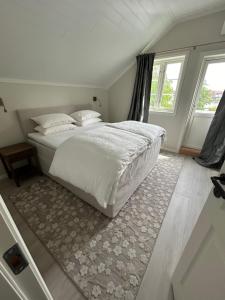 a bedroom with a white bed with a rug at Sjøgata Gjestehus No2 in Larvik