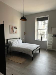 a white bedroom with a bed and a window at The Tower Suite - Town Centre, Spacious, 2 Bed, Sleeps 4 in Larne
