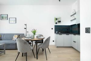 a living room with a table and chairs and a couch at Modern Apartment Nadmorska in Mrzeżyno with Parking near the Sea by Noclegi Renters in Mrzeżyno +12 photos