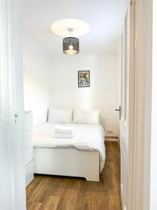 a white bedroom with a bed with white sheets at Folkestone Oasis - Central 2 Bedroom Apartment - Pets Welcome! in Folkestone