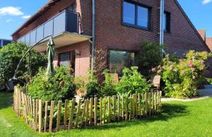 a house with a wooden fence in the yard at Ferienwohnung Nordwind - Haus Seeschwalbe in Wangerland