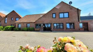 a brick house with windows and flowers in front of it at Ferienwohnung Nordwind - Haus Seeschwalbe in Wangerland +6 photos