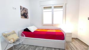 a bed in a room with a window and a chair at Enjoy this apartment, with two bedrooms in Sant Adria de Besos