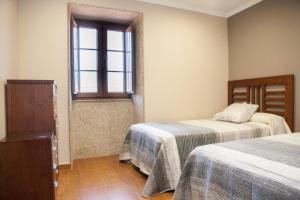 a room with two beds and a window at Casa De Rama in San Mamede de Carnota