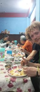 un gruppo di persone sedute a un tavolo che mangiano cibo di Anil Guest house and khajaghar a Rāmechhāp