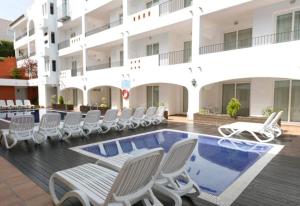 un hotel con sedie e una piscina e un edificio di Aparthotel Puerto Mar a Peñíscola