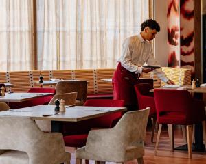 a man standing in a restaurant reading a newspaper at Rivage Hôtel & Spa Annecy in Annecy