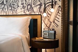 胡志明市Hotel Indigo Saigon the City by IHG的一间卧室配有一张床和一张桌子上的收音机 更多37张照片