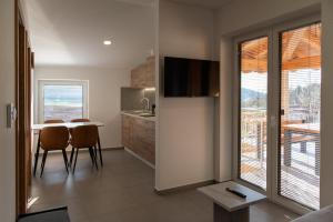 a kitchen and dining room with a table and a kitchen with a window at Apartments Pr' Užlejbvih in Podnanos