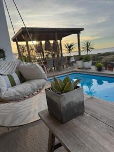 a patio with a couch and a table next to a pool at 105 On Beach, Whale Room in St. Helena Bay
