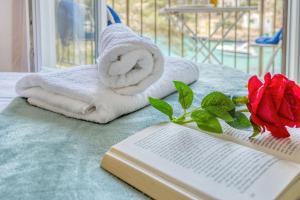 un libro, degli asciugamani e una rosa su un letto di Apartamentos Drac by dracmallorca a Cala Santanyi Altre 188 foto