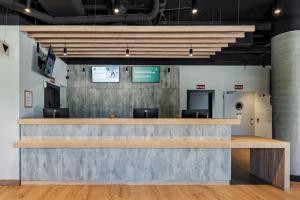 a lobby with a large concrete counter with chairs at ibis budget Madrid Aeropuerto in Madrid