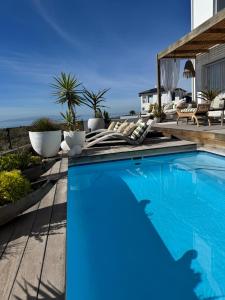 a blue swimming pool on a patio with a house at 105 on Beach, Flamingo Room in Stompneusbaai