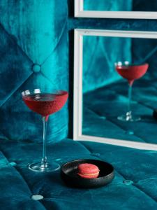two martini glasses and a plate with a red drink at Aria Hotel Budapest by Library Hotel Collection in Budapest