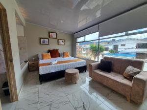 a bedroom with a bed and a couch and a window at HOTEL LUXEM in Bogotá