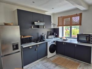 a large kitchen with blue cabinets and appliances at L'Abaca 25 in Sainte-Geneviève-lès-Gasny