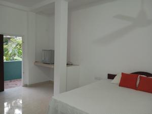 a white bedroom with a bed and a tv on a wall at Villa Sidu in Induruwa