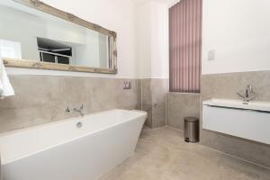 a bathroom with a tub and a sink and a mirror at The Buckingham Suite in Plymouth