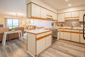 eine Küche mit weißen Schränken und ein Wohnzimmer in der Unterkunft Waterfront condo one block to Oceanfront in Sea Breeze
