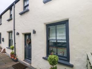 a white building with black windows and plants at Blacksmiths Cottage in Pembroke