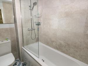 a bathroom with a shower with a tub and a toilet at Blacksmiths Cottage in Pembroke +34 photos